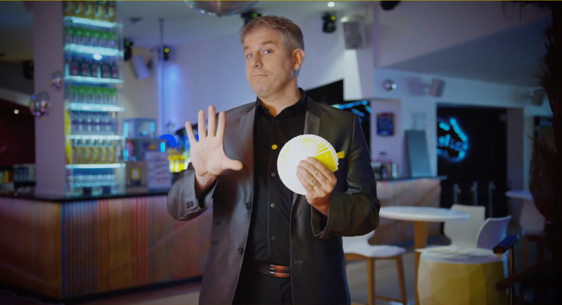Chris Torrente réalise un effet de magie avec un jeu de cartes et un éventail de cartes jaunes.